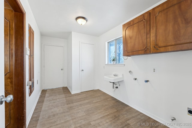 washroom featuring light wood-style floors, hookup for an electric dryer, cabinet space, and hookup for a gas dryer