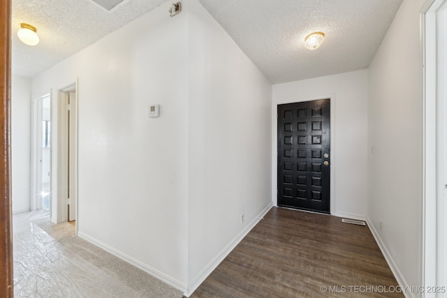 foyer entrance featuring a textured ceiling and baseboards