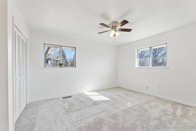 unfurnished bedroom with carpet, a closet, visible vents, a ceiling fan, and baseboards