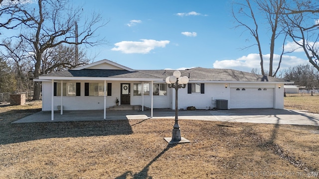 single story home featuring a garage, central AC unit, and concrete driveway