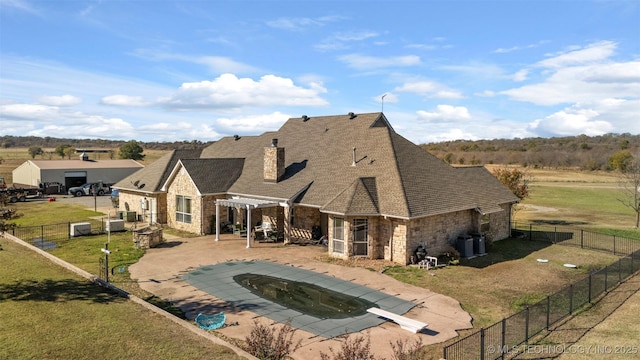 rear view of house with central AC unit, a covered pool, a yard, and a patio area