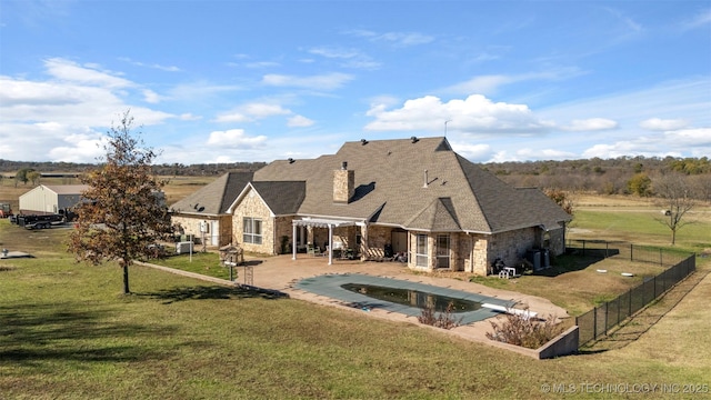 back of property with a yard, a patio area, and a covered pool