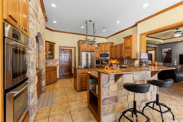 kitchen featuring a breakfast bar, crown molding, kitchen peninsula, stainless steel appliances, and decorative backsplash