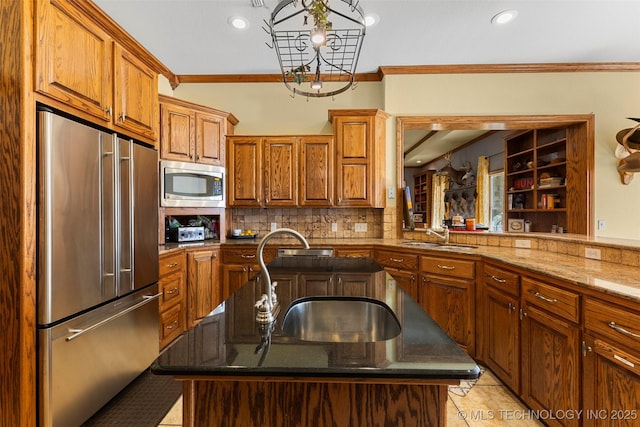 kitchen with sink, ornamental molding, stainless steel appliances, and an island with sink