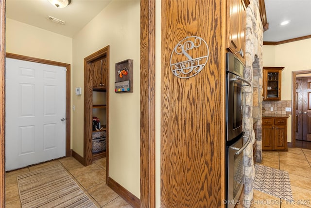 hall featuring light tile patterned floors and crown molding