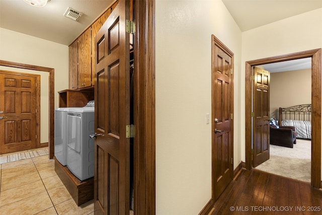 clothes washing area with cabinets, washer and dryer, and light wood-type flooring