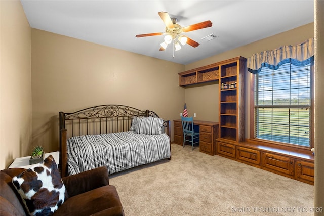 bedroom featuring light carpet, built in desk, and ceiling fan