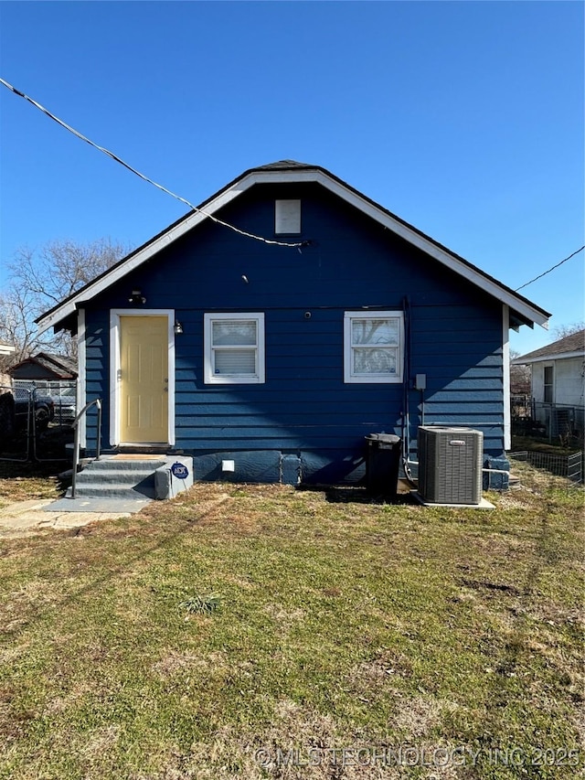 back of property featuring a yard and central AC