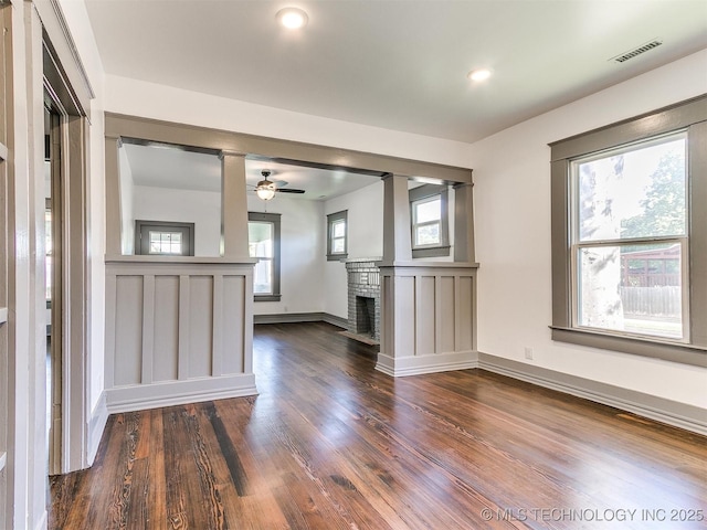 unfurnished living room with wood-type flooring, ceiling fan, and a fireplace