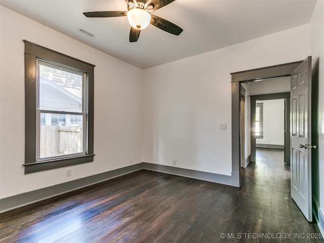 empty room featuring ceiling fan, dark hardwood / wood-style floors, and a healthy amount of sunlight