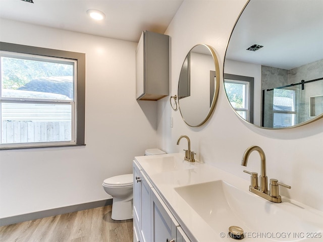 bathroom featuring hardwood / wood-style flooring, toilet, plenty of natural light, and a shower with shower door