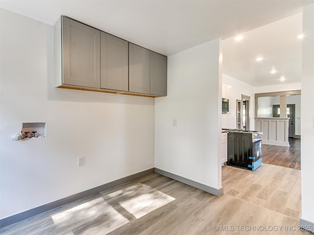 clothes washing area featuring cabinets, washer hookup, decorative columns, and light hardwood / wood-style flooring