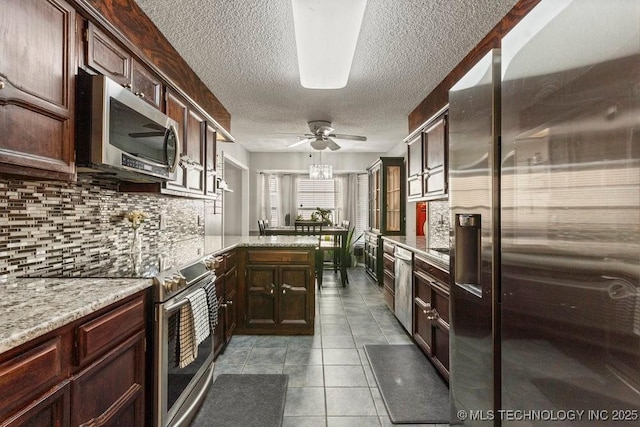 kitchen with light tile patterned floors, ceiling fan, stainless steel appliances, light stone countertops, and decorative backsplash