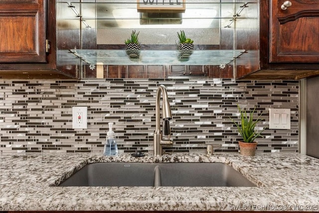 kitchen with light stone counters, sink, and backsplash