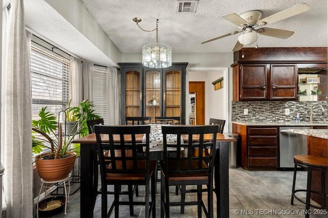 dining space with ceiling fan with notable chandelier, sink, and a textured ceiling