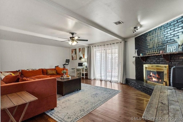 living room with ornamental molding, dark wood-type flooring, ceiling fan, and a fireplace