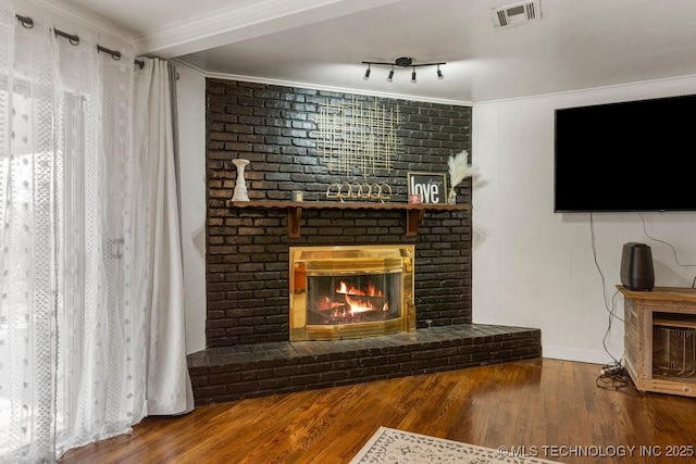 living room with ornamental molding, hardwood / wood-style floors, and a brick fireplace