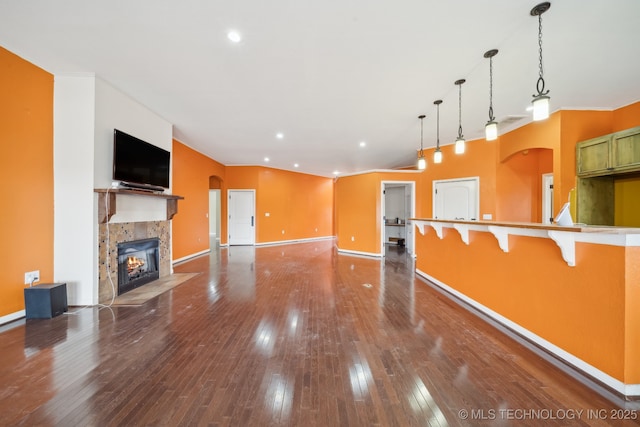 kitchen with a tile fireplace, wood-type flooring, a breakfast bar, and decorative light fixtures