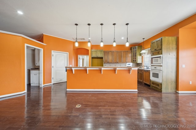 kitchen featuring a kitchen island, decorative light fixtures, tasteful backsplash, a kitchen breakfast bar, and white appliances