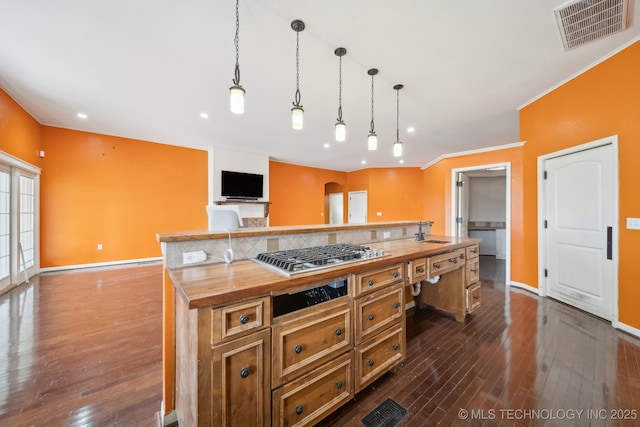 kitchen with sink, decorative light fixtures, stainless steel gas stovetop, a kitchen island with sink, and backsplash