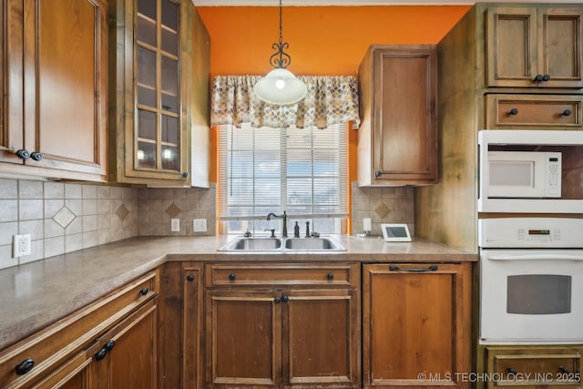 kitchen featuring white appliances, decorative light fixtures, sink, and decorative backsplash