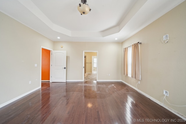 spare room featuring dark wood-type flooring and a raised ceiling