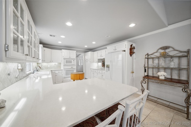 kitchen with crown molding, white cabinets, white appliances, and kitchen peninsula