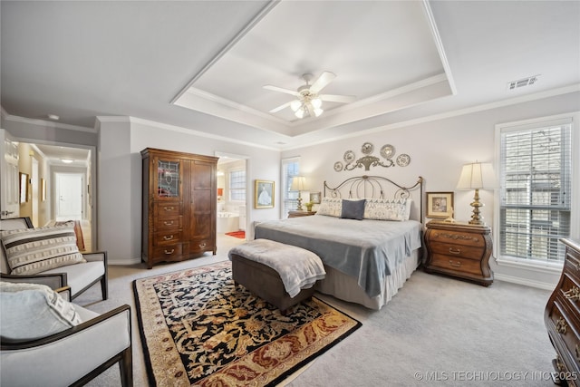 bedroom featuring connected bathroom, crown molding, light colored carpet, and a raised ceiling