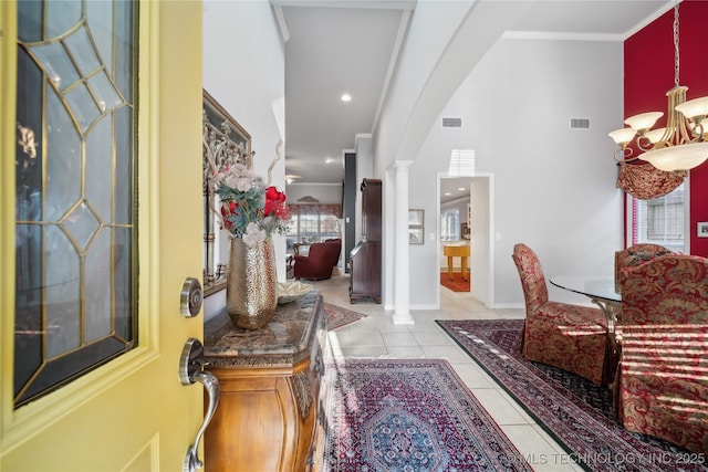 hallway featuring a notable chandelier, ornamental molding, decorative columns, and light tile patterned floors