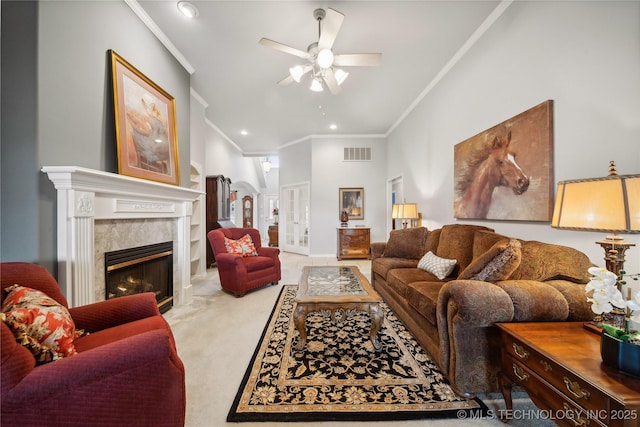 living room with ceiling fan, ornamental molding, a premium fireplace, and light carpet