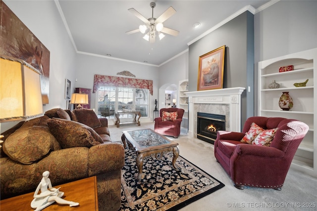 living room with ornamental molding, carpet floors, a towering ceiling, ceiling fan, and a fireplace