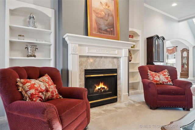 living area with built in shelves, ornamental molding, a fireplace, and carpet