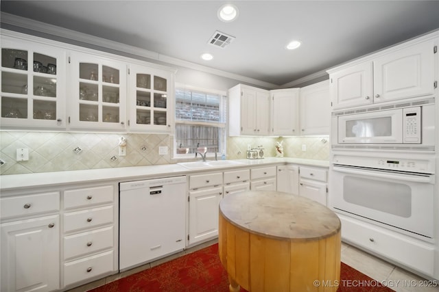 kitchen featuring sink, white appliances, white cabinetry, backsplash, and a center island