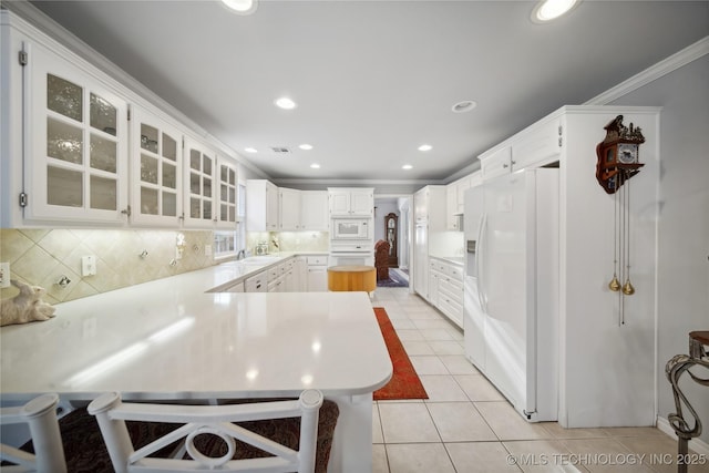 kitchen featuring light tile patterned flooring, sink, white cabinetry, kitchen peninsula, and white appliances