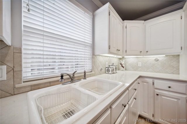 kitchen featuring tasteful backsplash, sink, and white cabinets