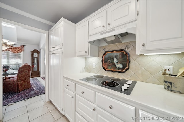 kitchen with light tile patterned flooring, white cabinetry, crown molding, white electric stovetop, and decorative backsplash