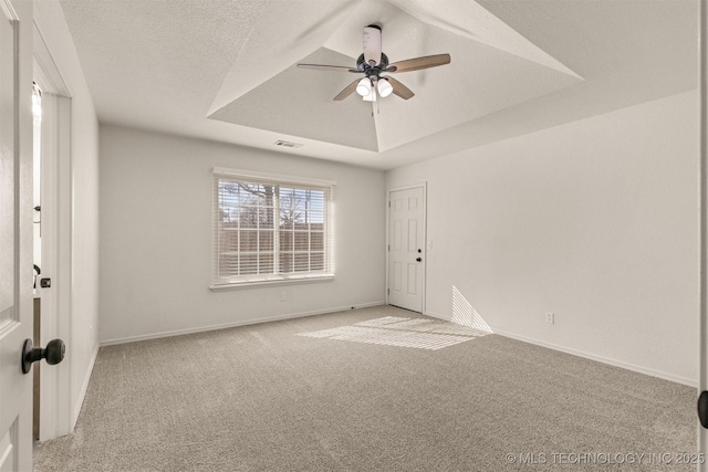 carpeted spare room with a raised ceiling, a textured ceiling, and ceiling fan