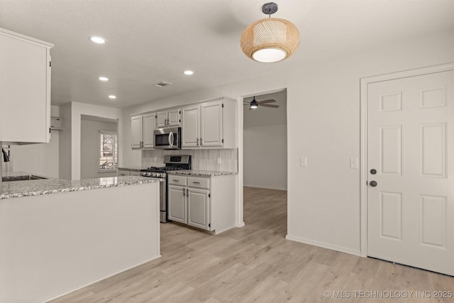 kitchen featuring appliances with stainless steel finishes, sink, white cabinets, decorative backsplash, and light stone counters