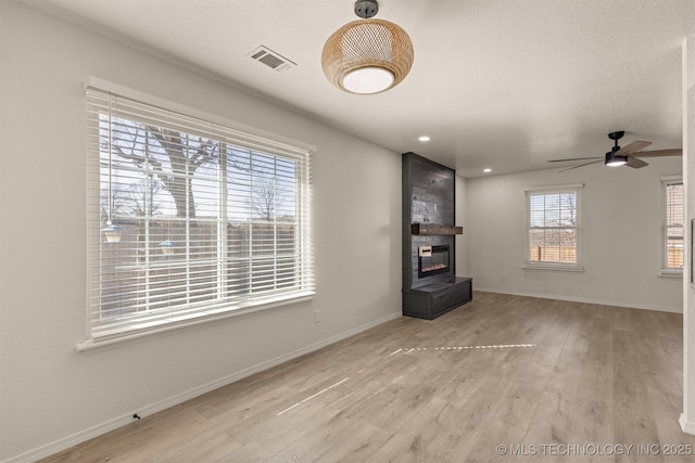 unfurnished living room with a fireplace, ceiling fan, and light wood-type flooring