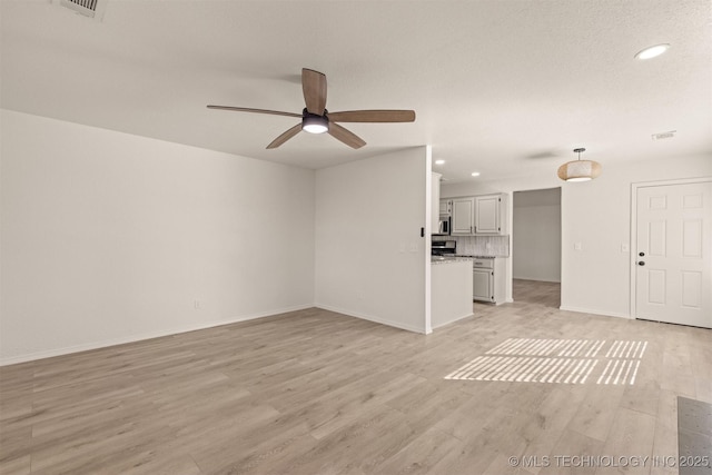 unfurnished living room featuring ceiling fan and light wood-type flooring