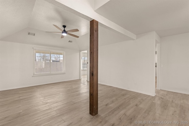 unfurnished living room featuring ceiling fan, lofted ceiling, light wood-type flooring, and a textured ceiling