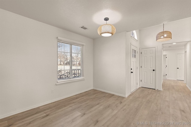 unfurnished room with light hardwood / wood-style flooring and a textured ceiling