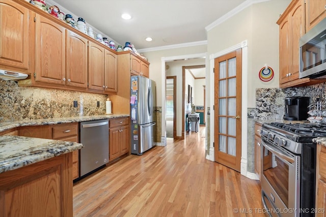 kitchen featuring stainless steel appliances, light stone countertops, decorative backsplash, and light wood-type flooring