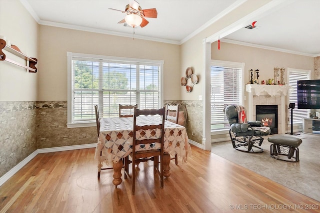 dining space featuring tile walls, crown molding, wood-type flooring, and a tile fireplace