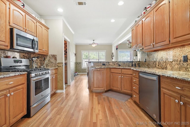 kitchen featuring light hardwood / wood-style flooring, stainless steel appliances, light stone counters, ornamental molding, and kitchen peninsula