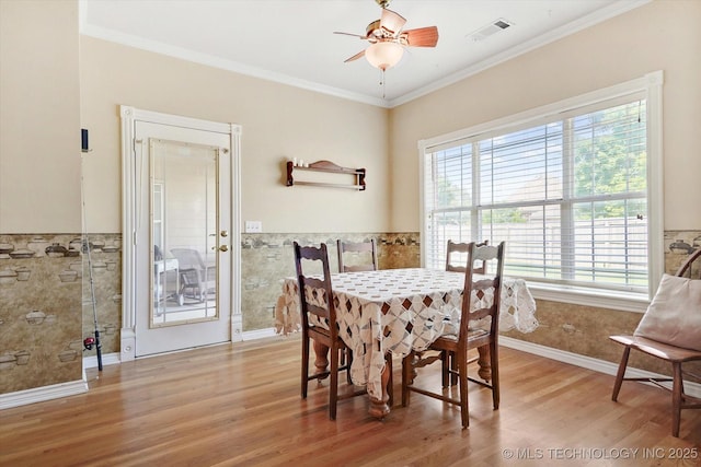 dining area with tile walls, crown molding, ceiling fan, and light wood-type flooring