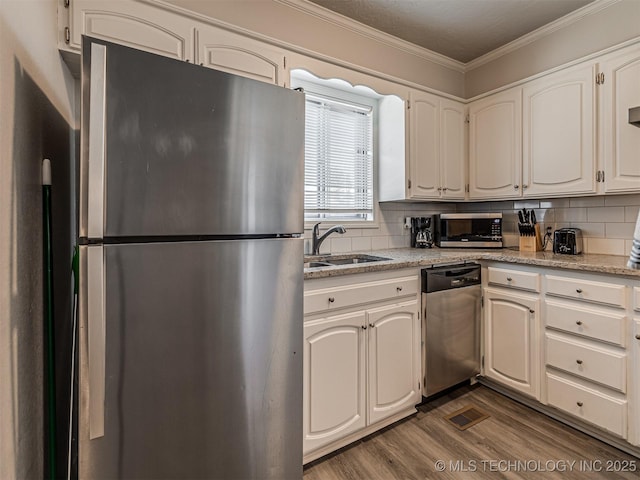 kitchen with tasteful backsplash, appliances with stainless steel finishes, sink, and white cabinets