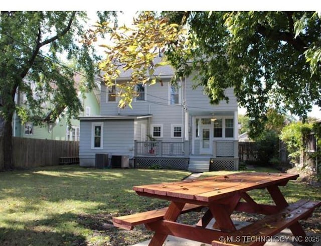 rear view of property with a deck, a lawn, and central air condition unit