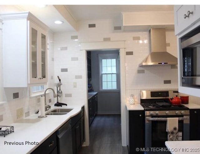 kitchen with black dishwasher, sink, white cabinets, gas stove, and wall chimney exhaust hood