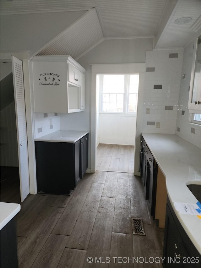 kitchen with vaulted ceiling, dark hardwood / wood-style floors, white cabinets, and decorative backsplash